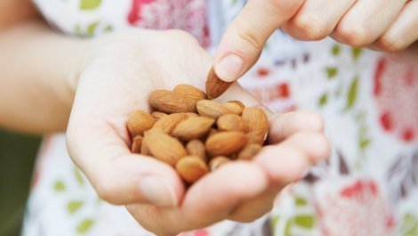 Woman Eating Handful Of Almonds