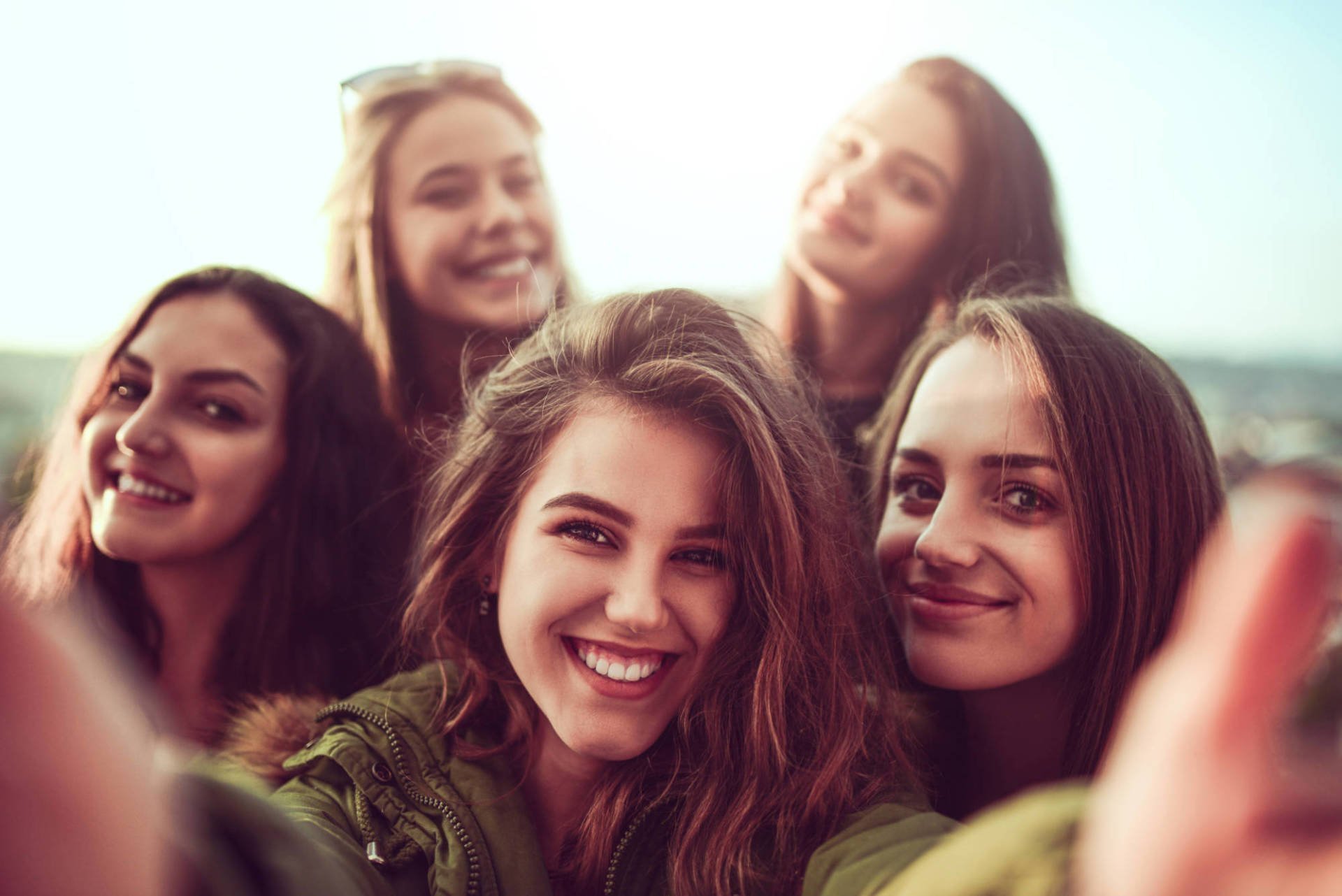 Group Of Smiling Girls Taking A Selfie Outdoors At Sunset