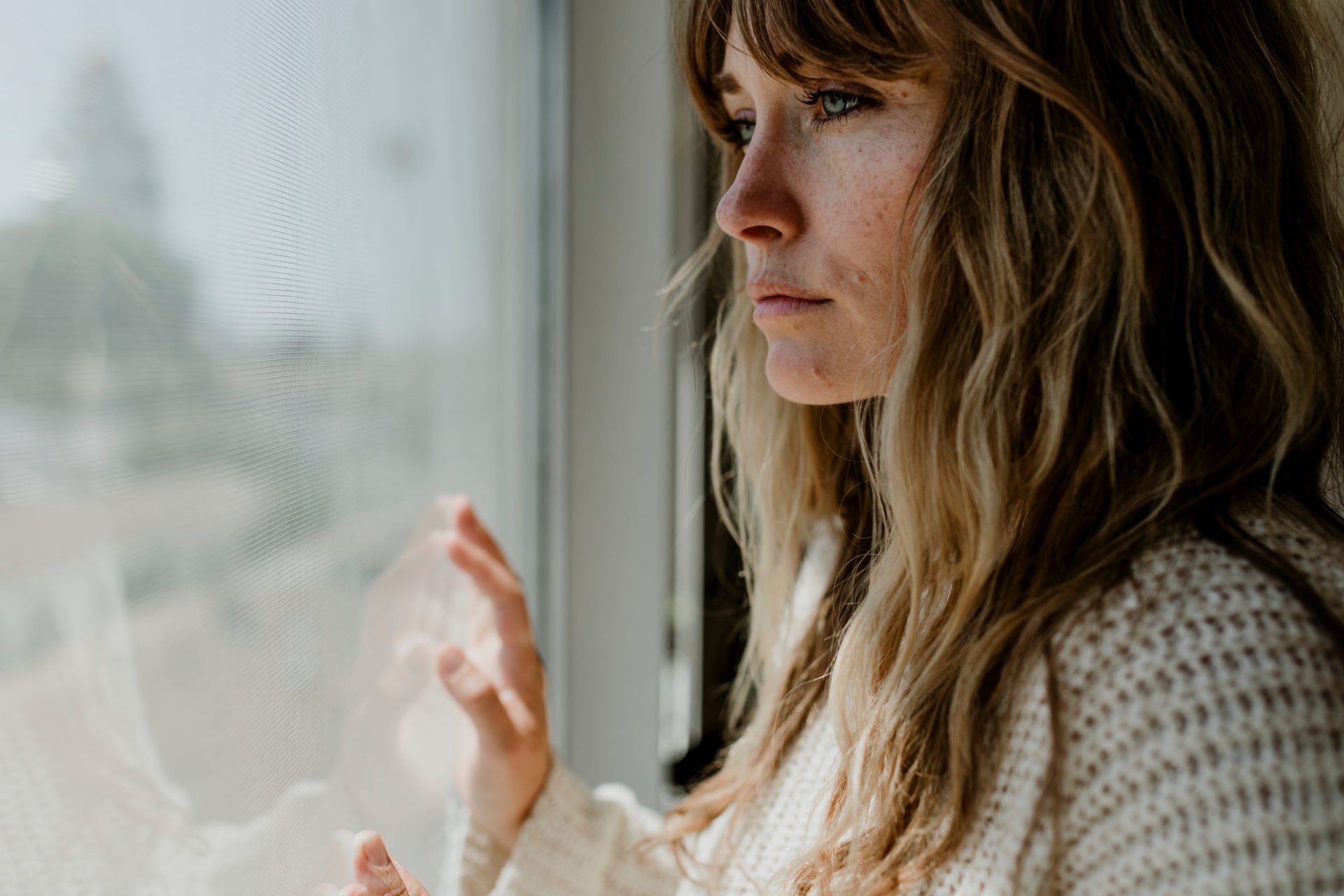 Sad Woman Staring Out The Window During A Lockdown