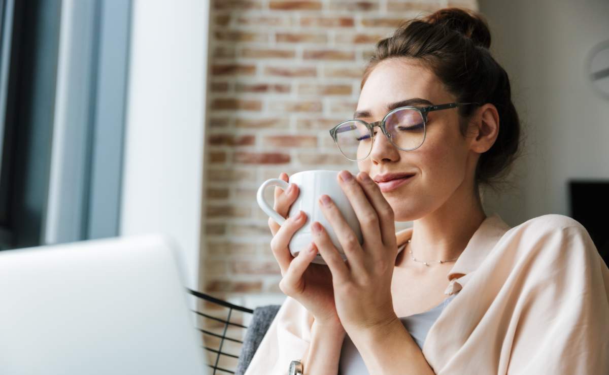 Image Of Woman Working With Laptop And Drinking Coffee While Sitting