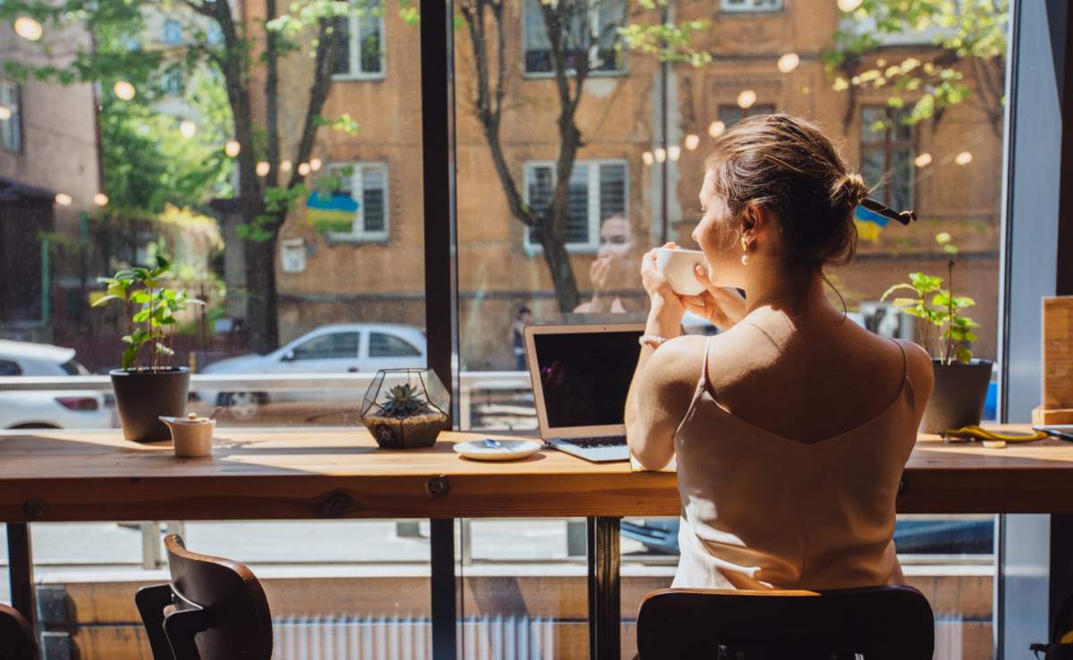 Caucasian Romantic Woman Blogger Relaxing Drinking Tea While Sitting Near The Window In Modern Loft Cafe Bar,female Freelancer Thinking About New Ideas During Work On Laptop Computer. Copy Space