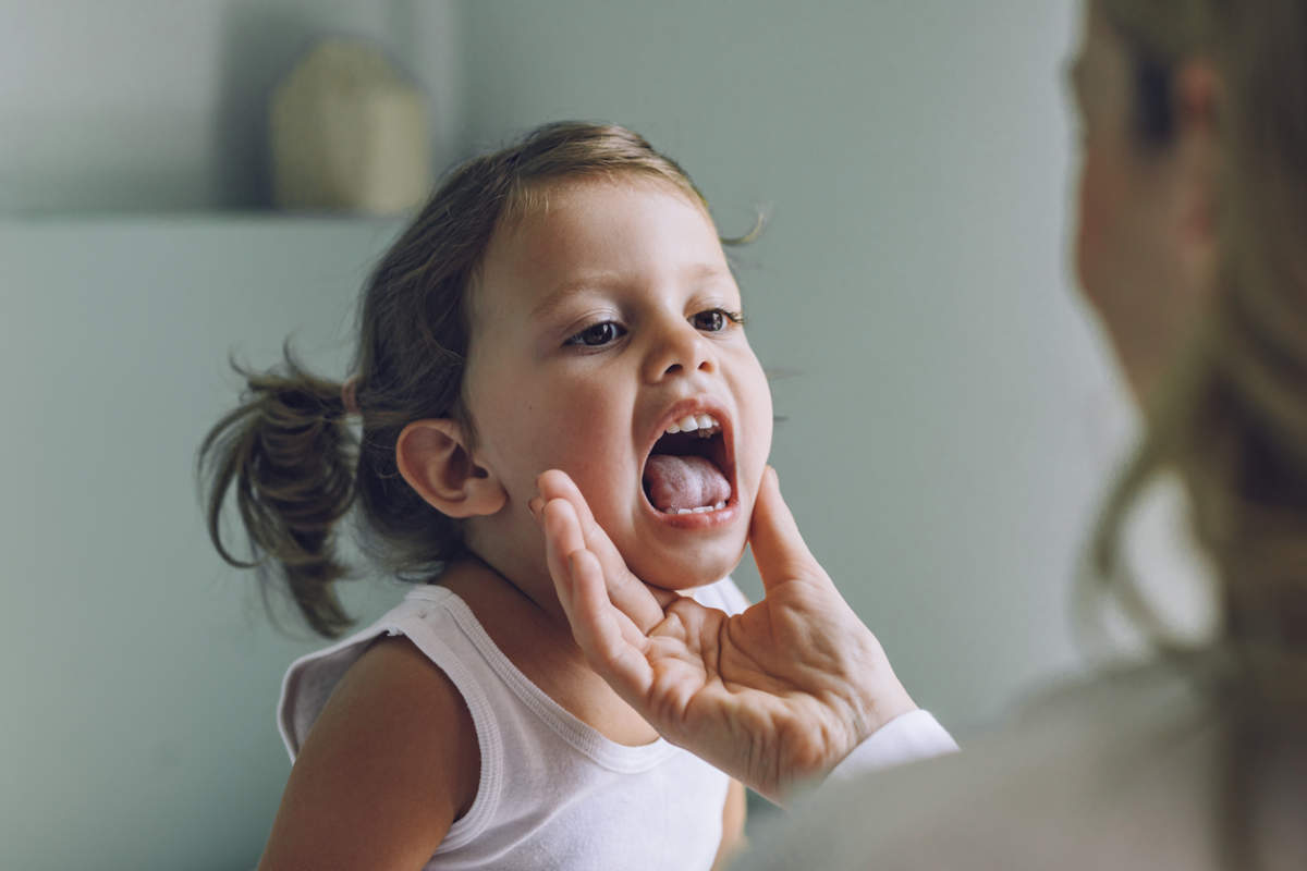 Child At A Medical Checkup: Pediatrician Examining A Little Girl's Throat