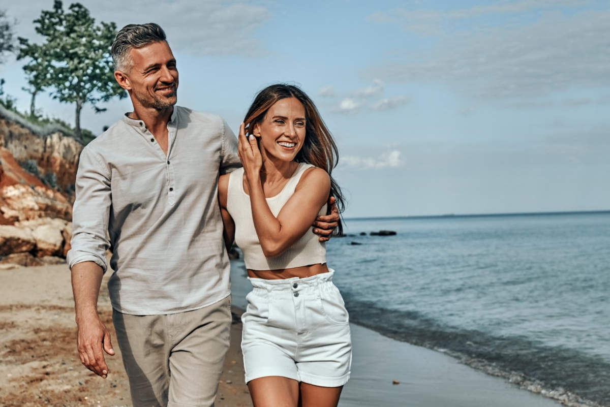 Happy Attractive Couple Walking On Beautiful Sunny Beach.