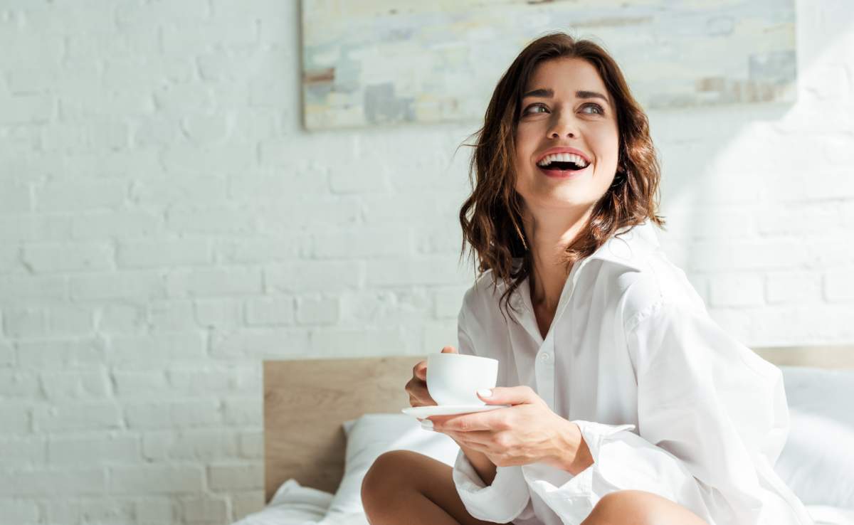 Attractive Woman In White Shirt Smiling And Holding Cup At Morning