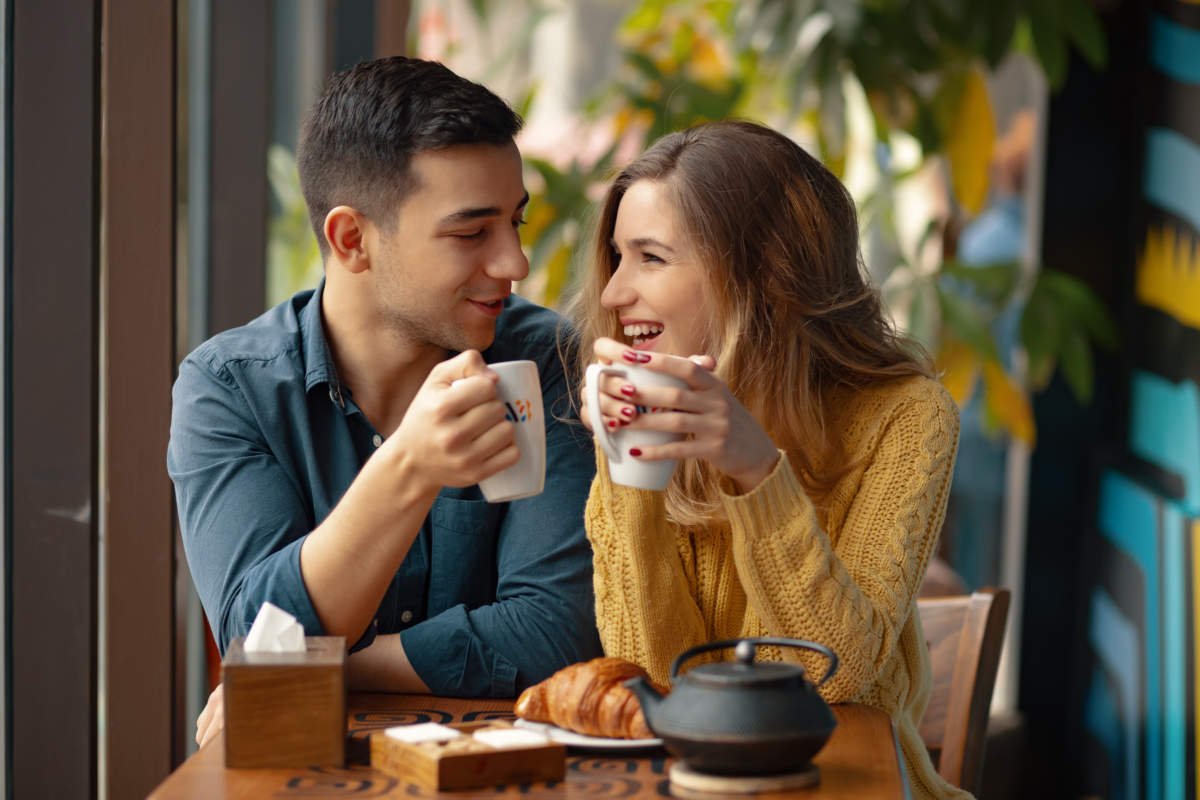 Young Couple In Love Sitting In A Cafe, Drinking Coffee
