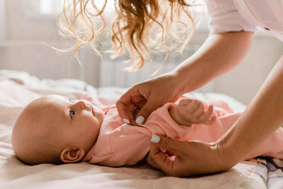 Mom With Her Baby Newborn Infant Kid Child At Home Take Care In The Bedroom Put On Clothes. Woman Family Women's Health And Maternity