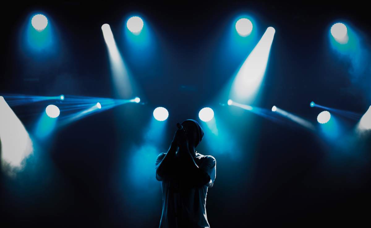 Silhouette Of Rap Singer Singing On Concert. Cool Young Rapper Performing Live On Stage In Bright Lights