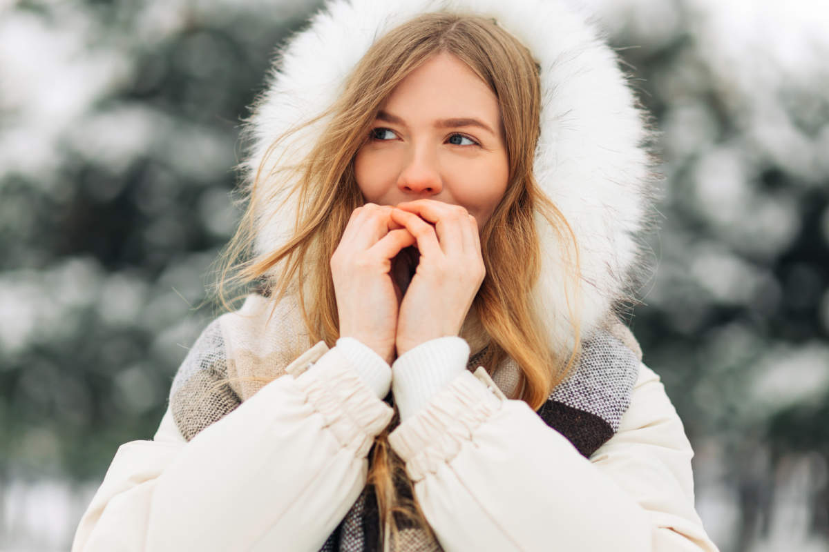 Girl Warming Up Her Hands In Warm Winter Clothes. Attractive Model Portrait Outdoors On A Cold Day