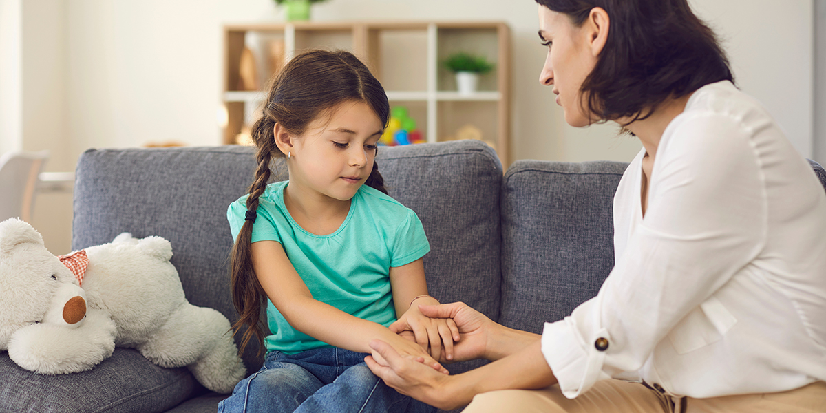 Mother Sitting With Daughter, Holding Her Hands, Talking To Her And Teaching Her Something