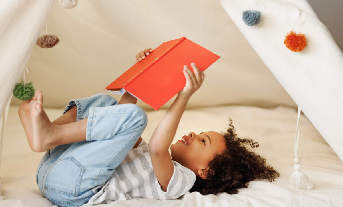 Cute Little African American Kid Curly Boy Reading Book In Play Tent