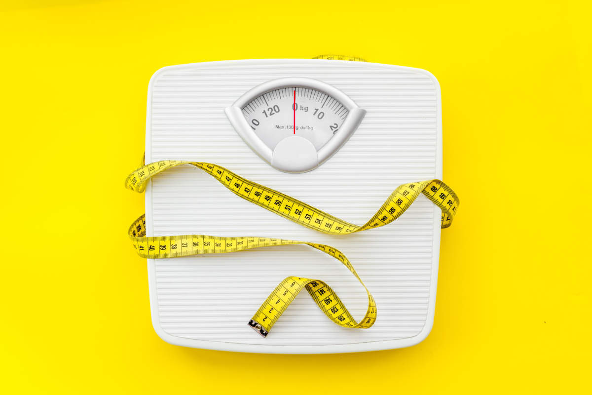 Bathroom Scales And Measuring Tape For Weight Loss Concept On Yellow Background Top View