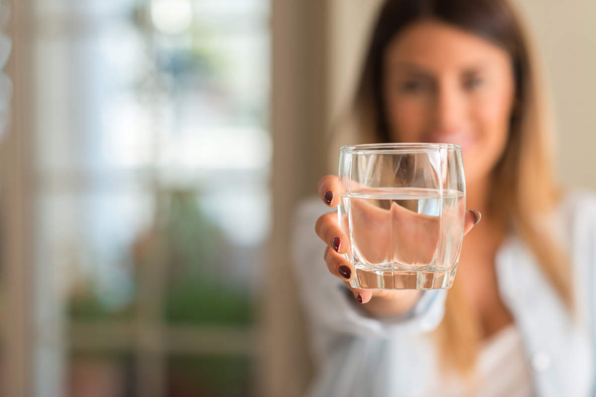 Beautiful Young Woman Smiling While Holding A Glass Of Water At