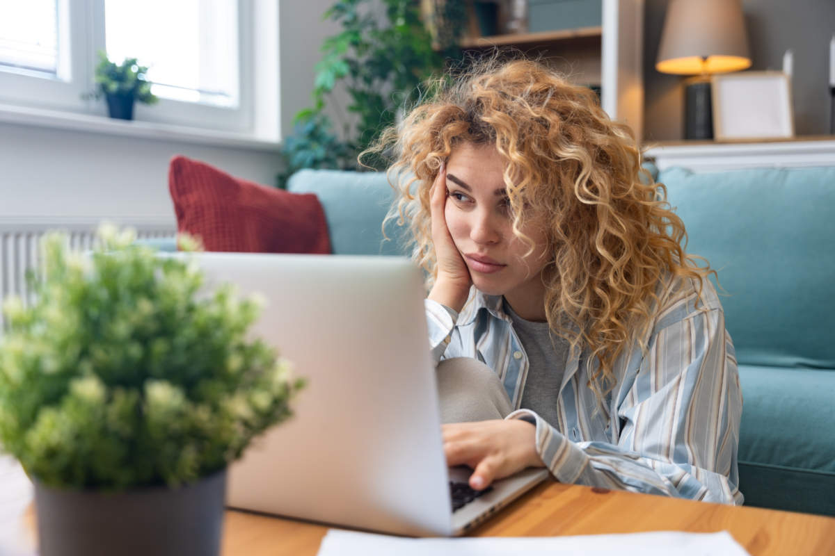 Young Woman Struggling With Focus While Working On Laptop On Floor, Surrounded By Printed Analytic, Battling Adhd, Mental Fatigue, Burnout, And The Pressure Of Modern Multitasking Expectations