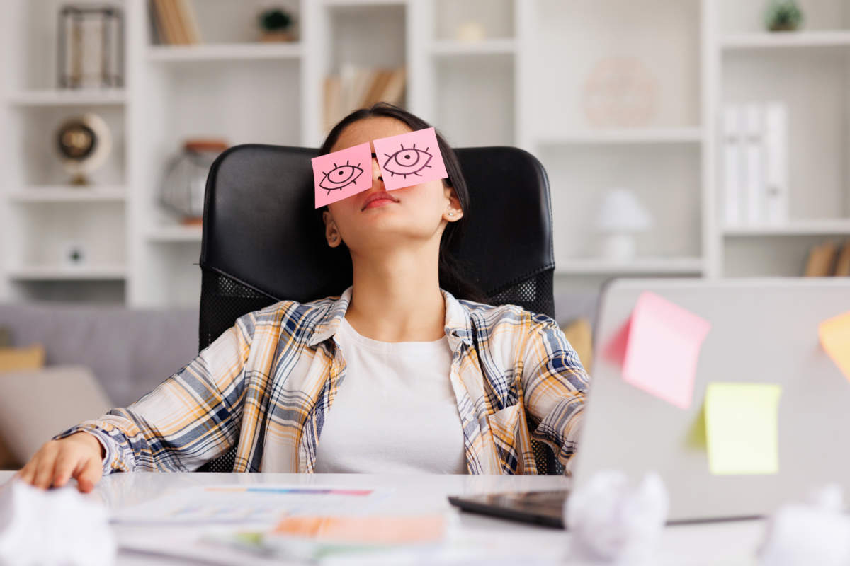 The Concept Of A Lot Of Work. Tired Indian Student Girl Sleeping With Stickers On Her Eyes While Sitting At The Table. Distracted Woman In Home Office.