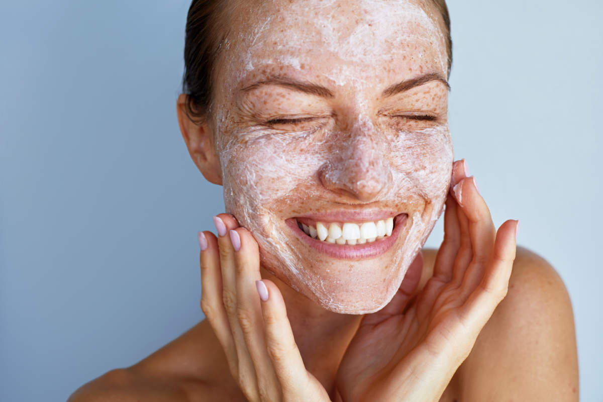 Overjoyed Young Woman With A Freckles Skin Care Beauty Portrait. Applying White Peeling Cosmetic Product To Whole Her Face. Dermatology. Exfoliating