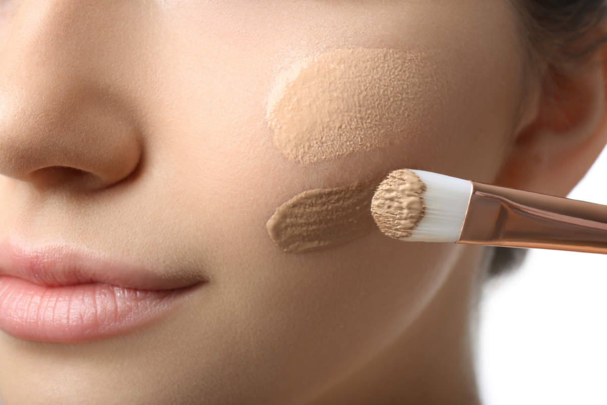 Girl Applying Foundation And Concealer With Brush On White Background, Closeup. Face Contouring
